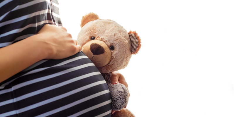 Pregnant girl holding teddy bear