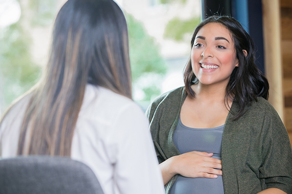 Hispanic woman discussing her pregnancy with midwife