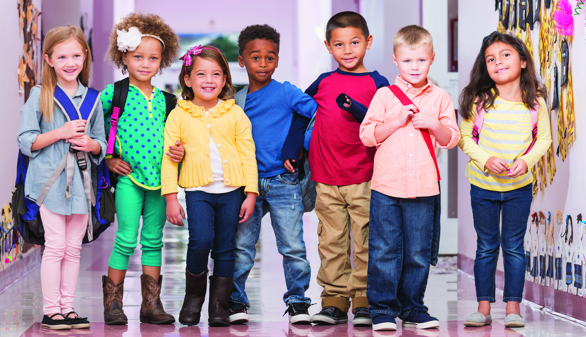 Diverse group of kindergartners stand in a hallway