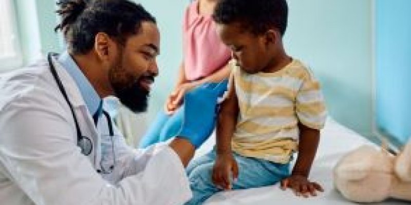 Black doctor with stethoscope examining black child's heart